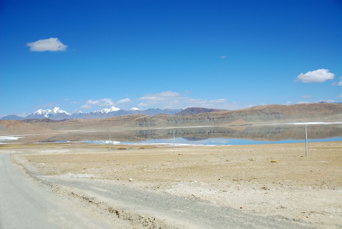 17 Drolung Tso Lake On The Drive To Saga With 6000m Peaks Northeast Of Saga The calm water of the Drolung Tso Lake reflects the hills and 6000m mountains northeast of Saga.